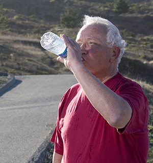 Man drinking water outdoors.