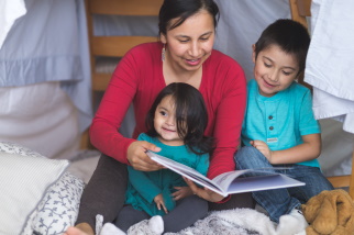 Mother and two children sitting on the floor reading a book