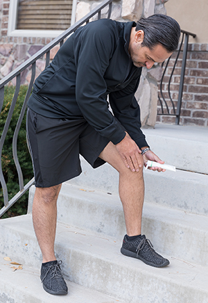 Man putting ointment on knee before exercise.