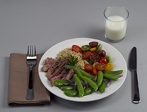 Dinner plate with balanced portions of meat, vegetables, and starch, with glass of milk.