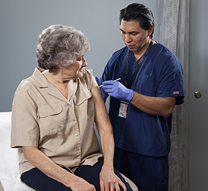 Healthcare provider giving injection in woman's upper arm.